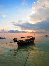 Fishing boat in sea against sky during sunset