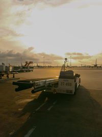 Airplane on airport runway against sky during sunset