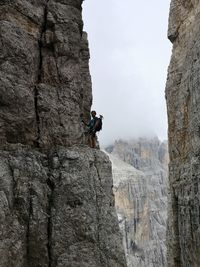 Side view of person on rock by mountains