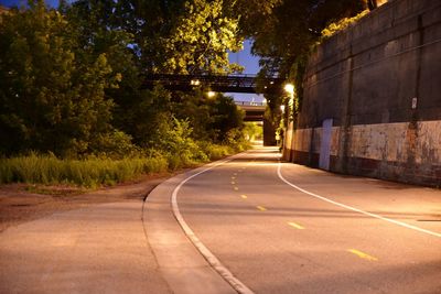 Empty road amidst trees in city