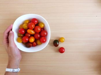 High angle view of hand holding strawberries on table