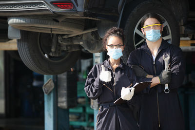 Portrait of mechanics wearing mas at garage