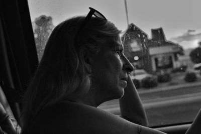 Side view of young woman looking through window