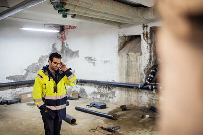 Smiling manual worker talking on phone in basement