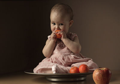 Close-up of boy eating fruit against white background