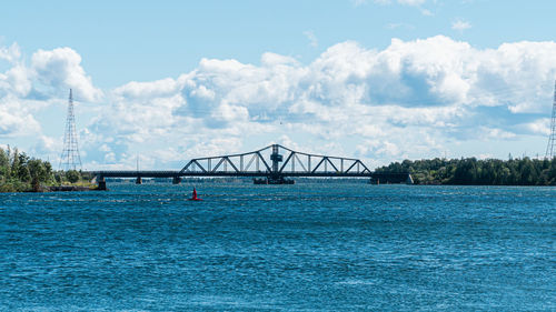 Bridge over river against cloudy sky