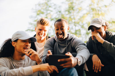 Smiling friends looking at mobile phone in skateboard park