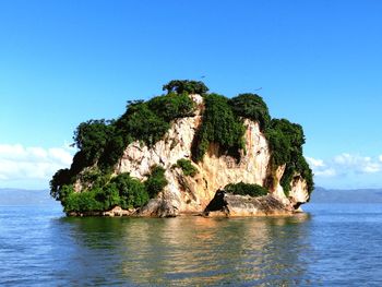 Rock formation in sea against blue sky