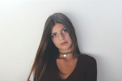 Portrait of young woman against white wall