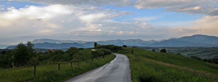 Road amidst agricultural field against sky
