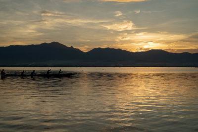Silhouette boats in lake against sky during sunset