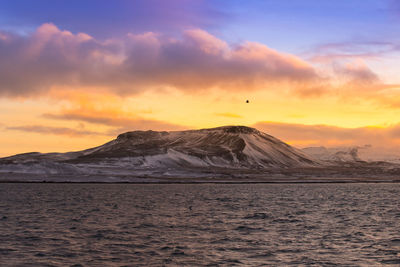 Scenic view of sea and mountains against sky during sunset