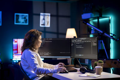 Rear view of woman using laptop at office
