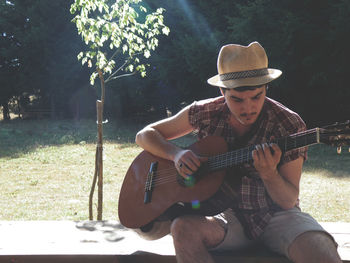 Portrait of man playing guitar in park