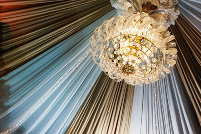 Full frame shot of ceiling with chandelier with decorative white and brown curtain sheets.