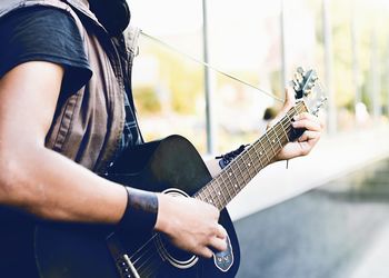 Midsection of man playing guitar