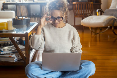 Portrait of young woman using mobile phone while sitting on table