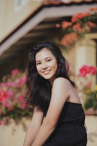 Portrait of young woman standing against plants