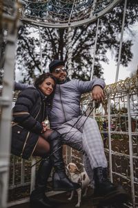 Portrait of couple with dog sitting at park