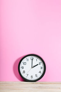 Close-up of clock on table against wall