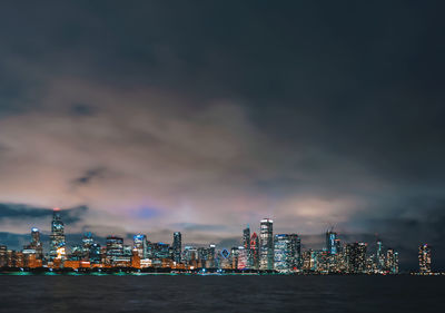 Illuminated buildings in front of river at night