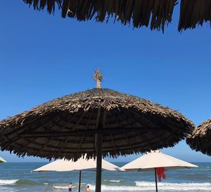 Traditional windmill on beach against clear blue sky
