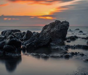 Rocks on beach against sky during sunset