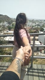 Midsection of woman sitting on railing against balcony