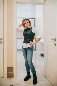 Full length portrait of a beautiful slender sassy woman in a doorway indoors. in a leather corset