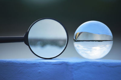 Close-up of crystal ball and magnifying glass on retaining wall