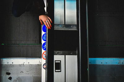 Midsection of woman wearing red nail polish standing on escalator