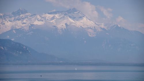 Scenic view of sea and snowcapped mountains against sky