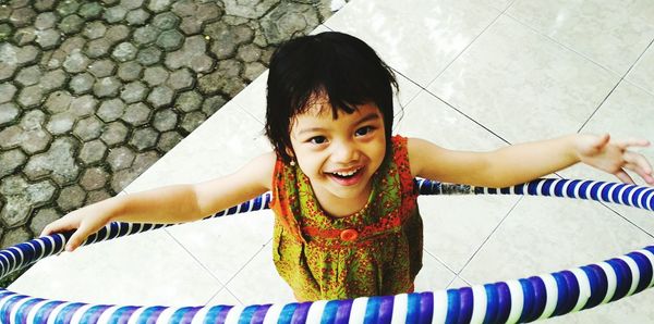 Portrait of happy girl with plastic hoop standing outdoors