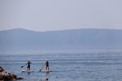 People enjoying in sea against sky