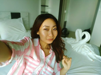 Portrait of young asian woman sitting on bed in hotel