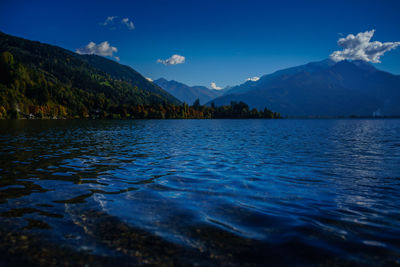 Scenic view of lake and mountains against blue sky