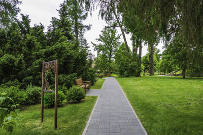 Stone paved pathway with green lawns and tree on both sides in park