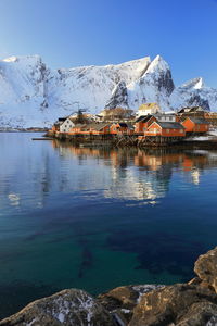 Stilt houses by lake against snowcapped mountains