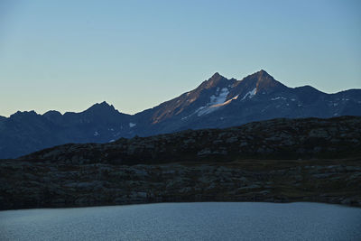 Scenic view of lake and mountains against clear blue sky