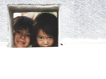 Portrait of siblings looking through window