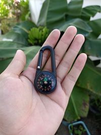 Close-up of hand holding navigational compass against plants