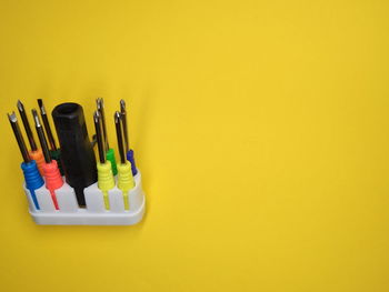 High angle view of multi colored pencils against yellow background