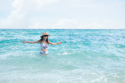 Young woman enjoying in sea against sky