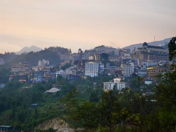 Buildings in town against sky during sunset