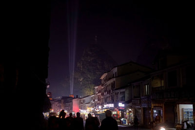 Crowd in city against sky at night