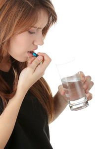 Midsection of woman drinking glass against white background