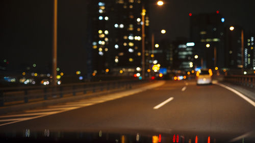 Cars on illuminated city street at night