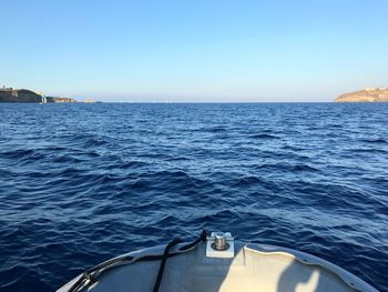 Boat sailing in sea against clear blue sky