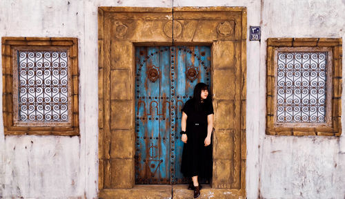 Woman standing against door of building