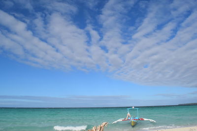 High angle view of boat moored on sea against cloudy sky